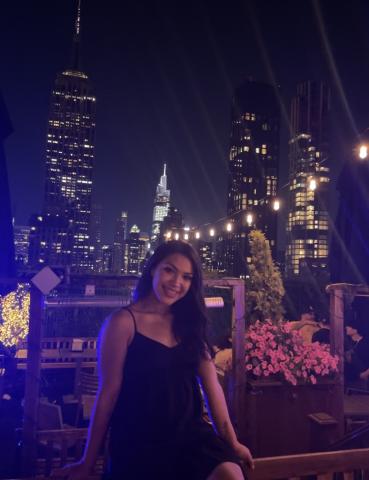 Janet sitting in a rooftop, with a background of skyscrapers.
