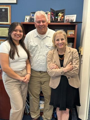 Luz Vázquez standing at an office with a couple.