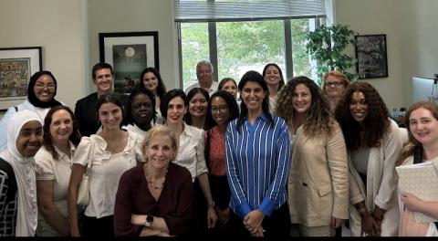 Luz Vazquez standing with a group of people in a meeting room.